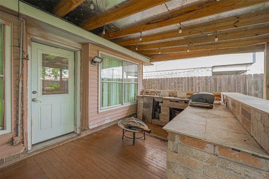 Outdoor patio with a built-in barbecue area and a countertop. Outdoor Kitchen needs some finishing touches. The space features wood paneling, string lights, and a view of a fenced backyard, making it ideal for outdoor entertaining.