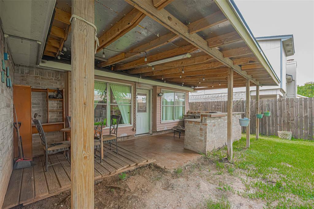 A cozy backyard patio with a wooden pergola, providing shade and a rustic feel