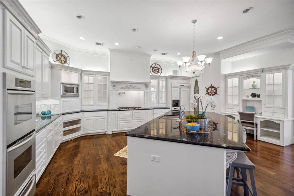 Kitchen with double ovens, dual dishwashers, warming drawer, pot-filer, desk & glass fronted hutch, abundant cabinets & a giant eat-at island.