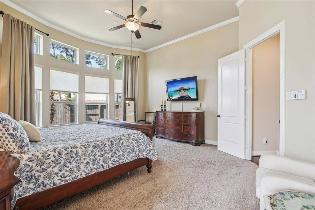 Spacious primary bedroom boasts a large bay window with floor-to-ceiling glass panels that flood the room with natural light and create a serene retreat.