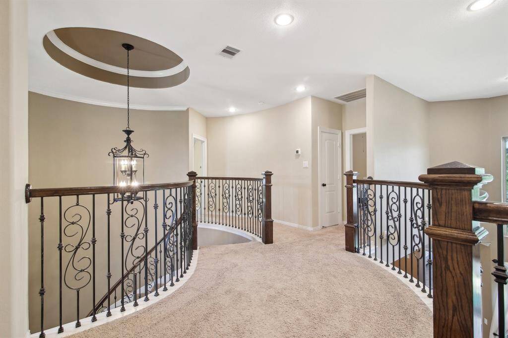 The upstairs hall features a wide catwalk with wrought iron spindles, adding architectural interest and an open, airy feel to the home’s upper level.