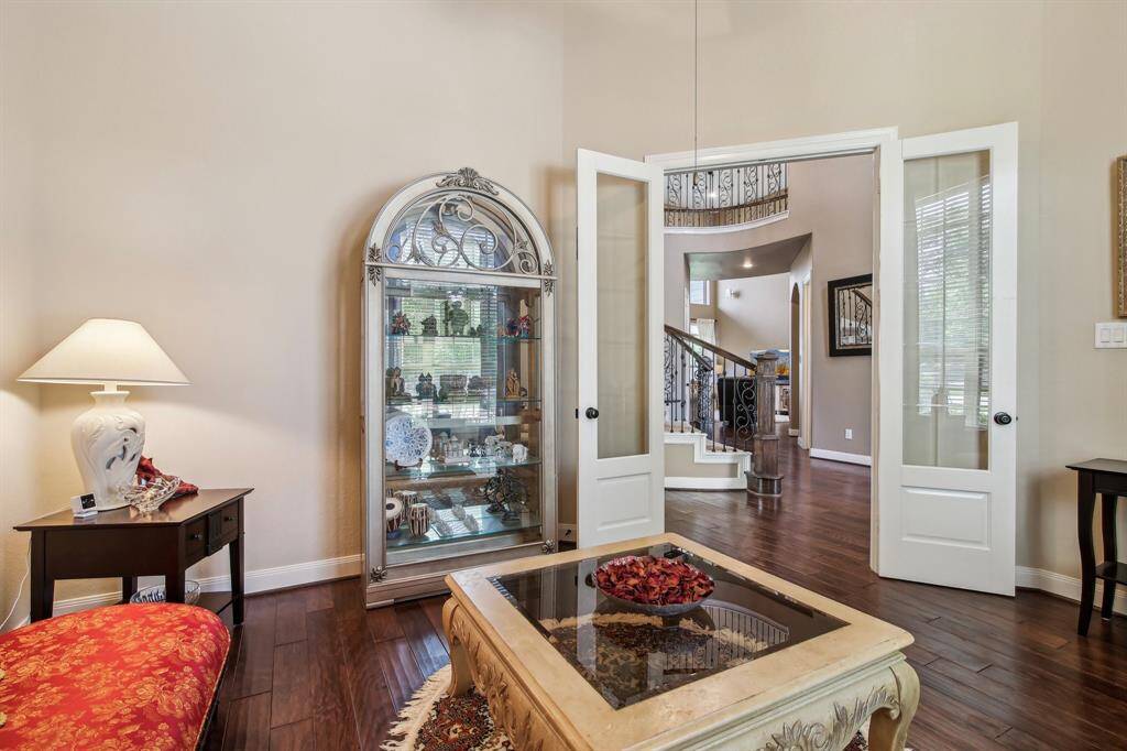 Private home office just off the entry, featuring glass French doors, a soaring ceiling with rich wood beams, and an abundance of natural light — the perfect blend of style and productivity.