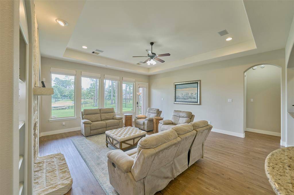 Step into this welcoming family room with ample seating, elegant tray ceilings, and large windows that flood the space with natural light and offer tranquil views of the lush outdoors.