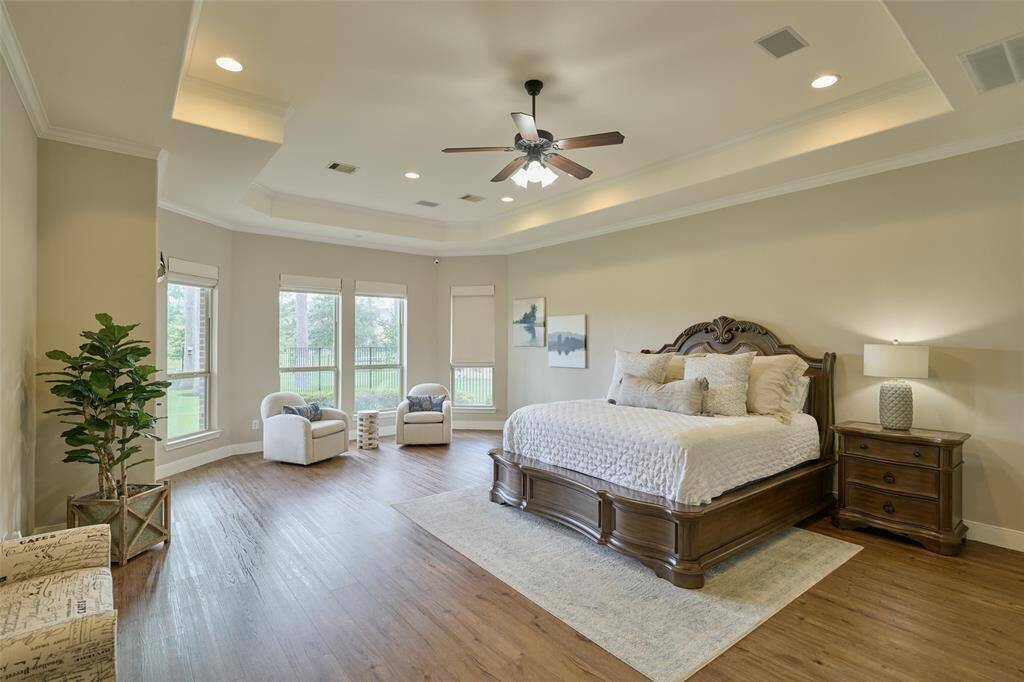 Discover a spacious primary bedroom featuring an elegant tray ceiling, abundant natural light, and a serene sitting area with stunning lake views.