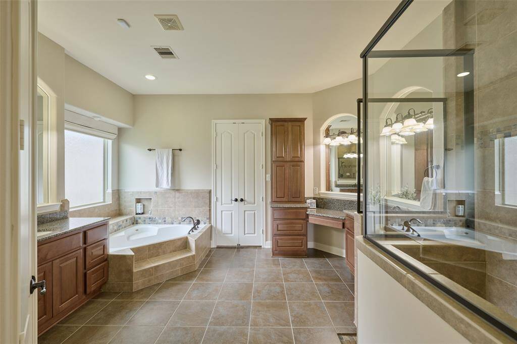 Experience luxury in this spacious primary bath featuring a large soaking tub, elegant cabinetry, walk-in shower, dual vanities, and a private water closet.