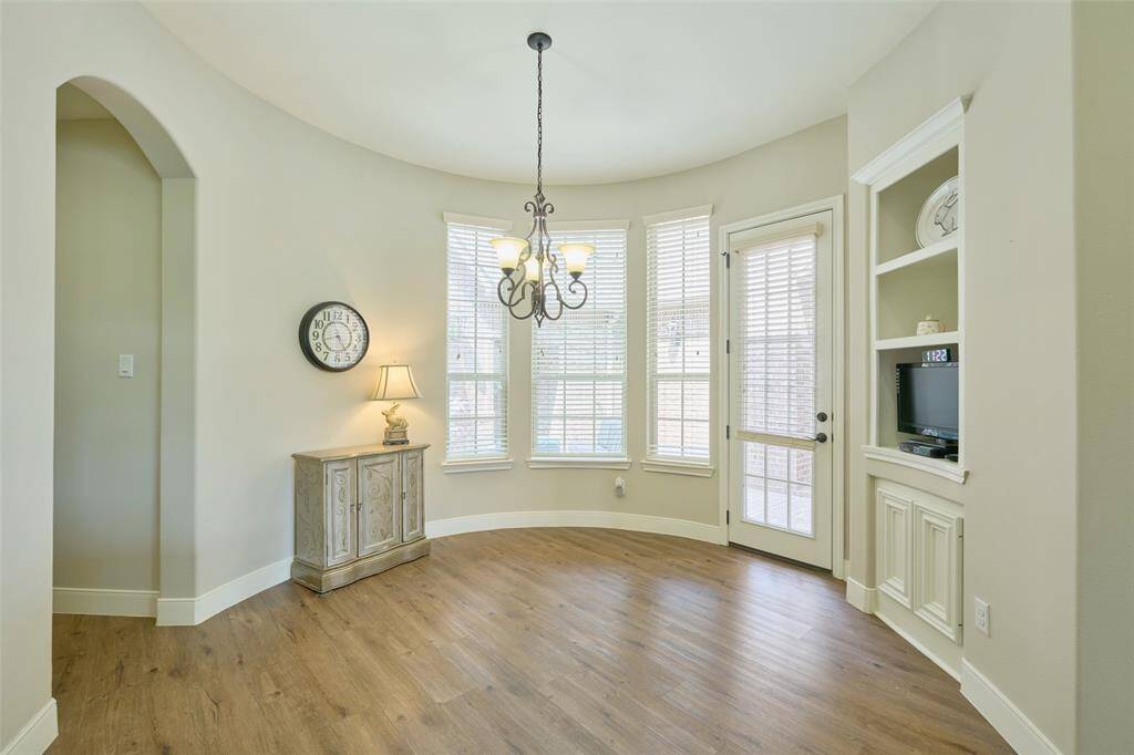 Bright breakfast nook with elegant flooring, courtyard views, and charming built-in shelving. Ideal for cozy mornings!