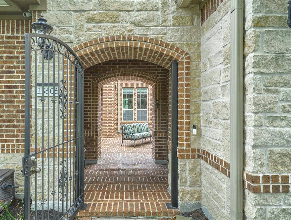 Discover your new home through an elegant wrought iron gate and charming brick archway, offering a warm welcome.