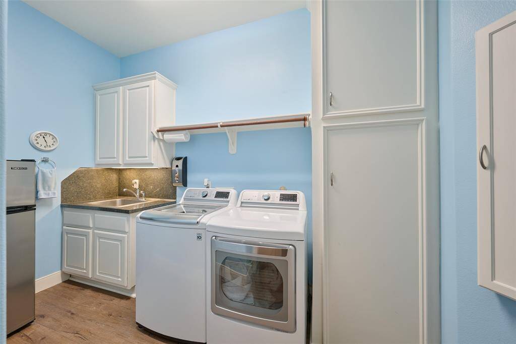 Modern laundry room with sleek appliances, generous storage, and a handy sink.