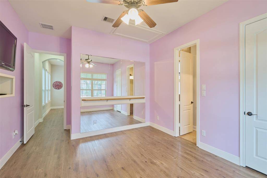 This bedroom offers a built-in ballet barre and wall-mounted TV, ideal for dance enthusiasts and cozy relaxation.