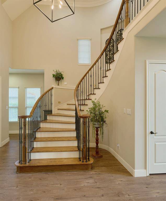 Stunning stairwell with a graceful curved staircase, featuring wrought iron rails and warm wood steps leading to second floor.