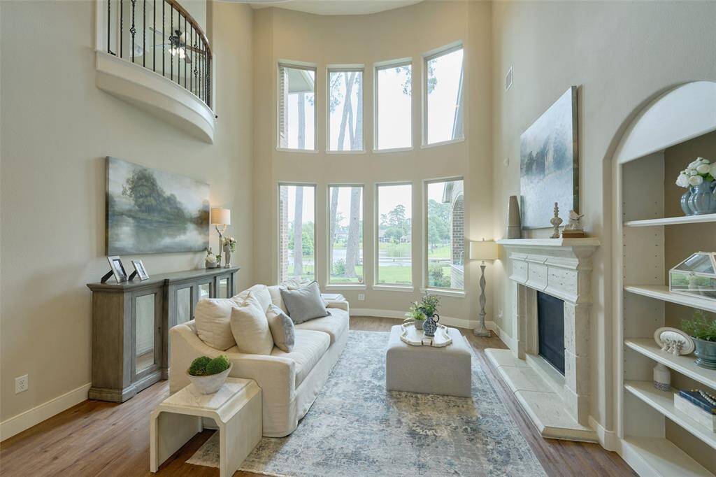 Discover sophistication in this bright living room with high ceilings, large windows offering tranquil views, and a cozy fireplace.