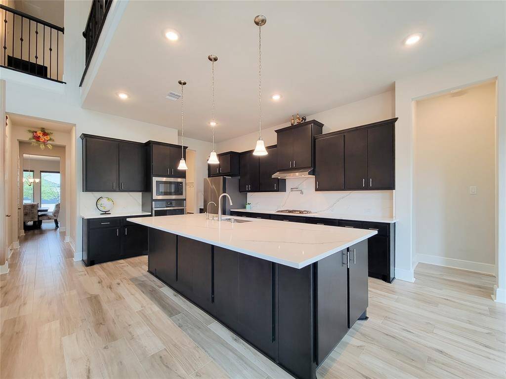 Pretty pendant lights over the huge island (close to 11x5) with room for bar stools. Ton of storage & counter space.
