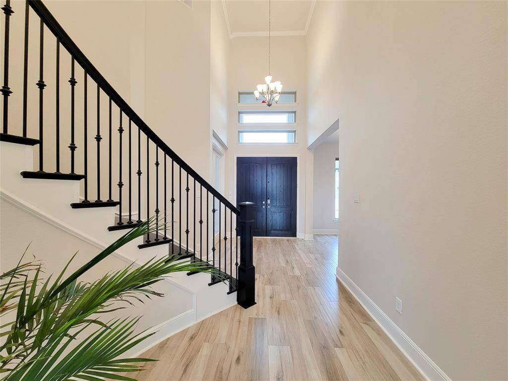 Impressive Foyer with curved staircase & two-story high ceilings. Extensive wood like tile floor throughout the downstairs area.