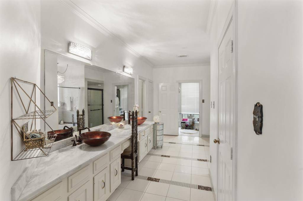 Custom Primary bathroom that is connected to the Primary Bedroom offering double sinks, vanity area, stone counter tops and his/her walk-in closets.