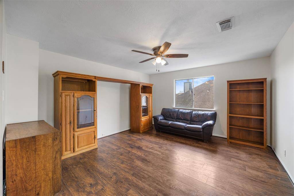 Bright and spacious gameroom with hardwood floors and neutral walls. It features a ceiling fan, and a window providing natural light,