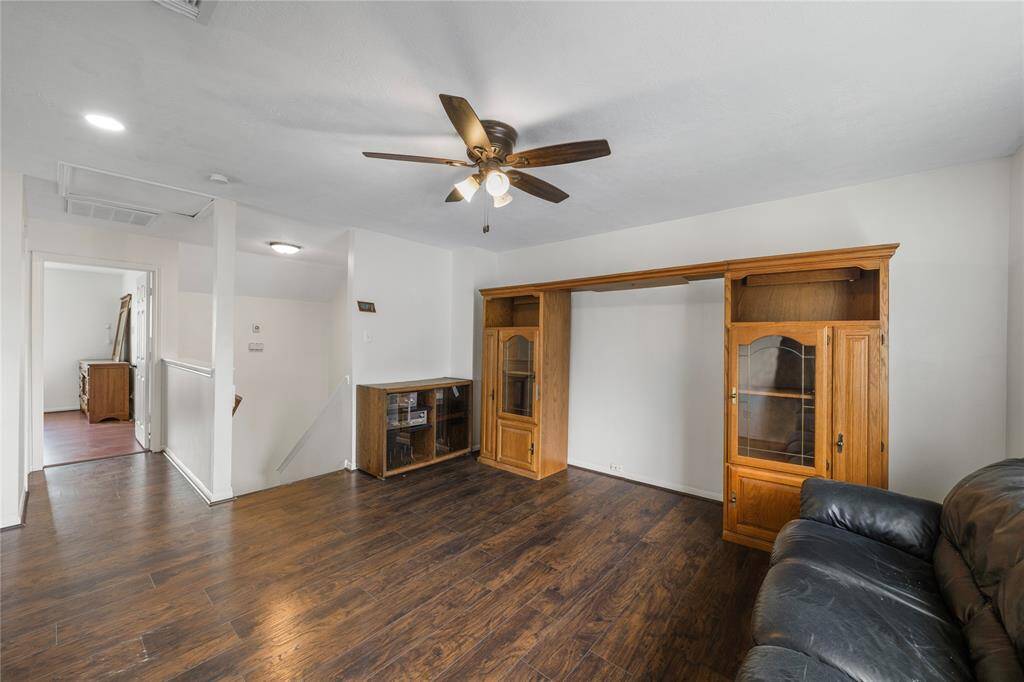 Another view of gameroom features hardwood flooring, a ceiling fan. It has an open layout that connects to other areas, offering a versatile living space.