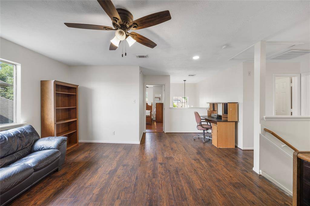 Gameroom features a spacious open layout with wood flooring, a ceiling fan, and abundant natural light making it ideal for both relaxation and work.
