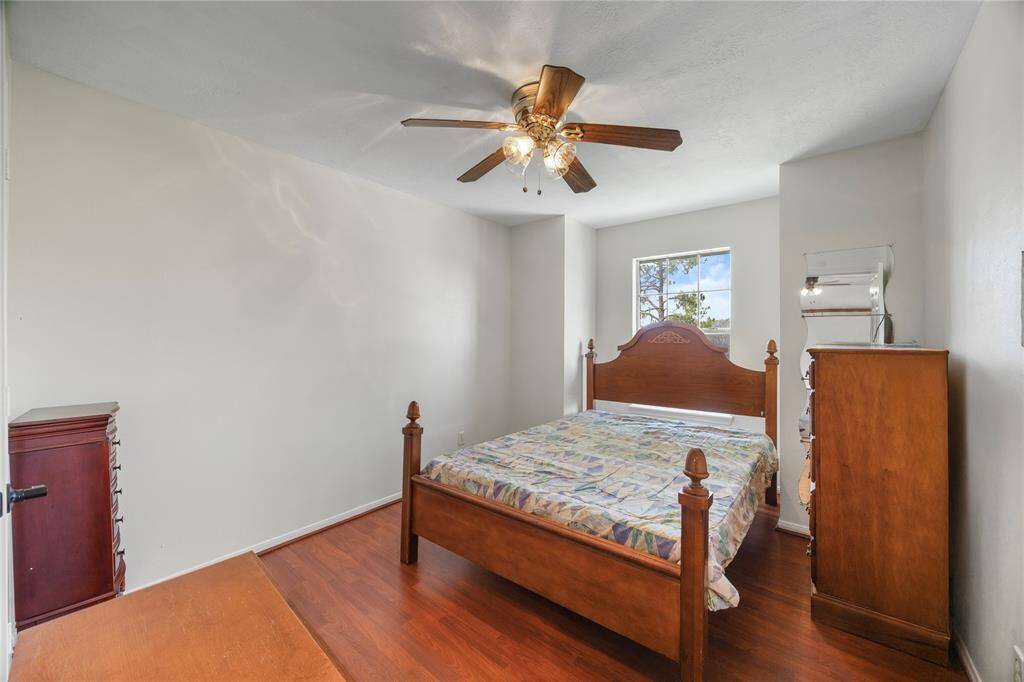 This  2nd bedroom features hardwood floors, a ceiling fan with lights, and a single window that lets in natural light, creating a cozy and inviting space.