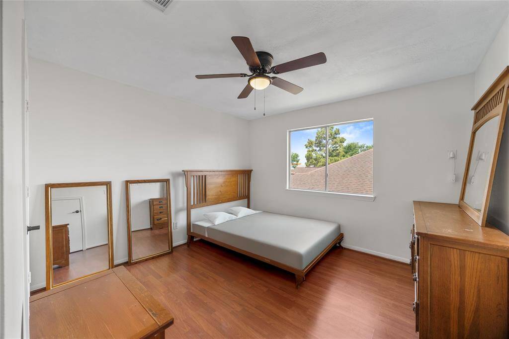 The 3rd bedroom features hardwood floors, a ceiling fan, and a large window offering natural light.