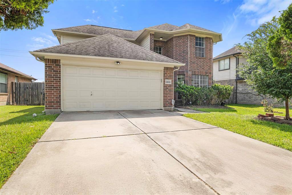 The driveway is spacious, and the house features large windows for ample natural light. It's situated in a residential neighborhood, offering a welcoming and well-maintained appearance.