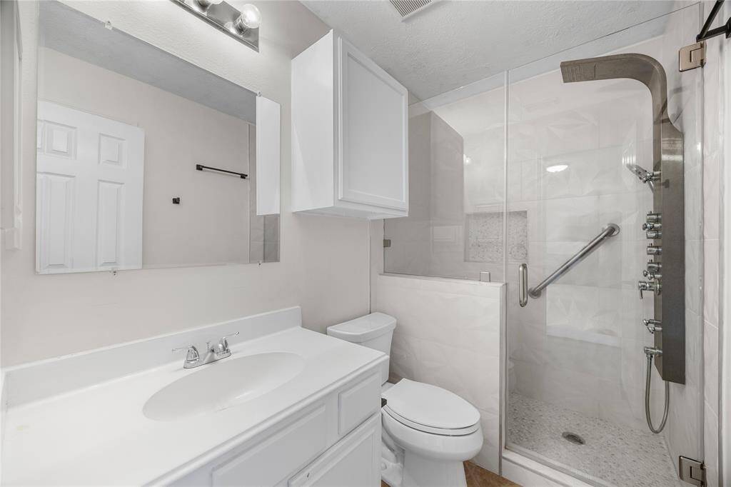This bathroom features a modern design with a sleek glass shower enclosure, a spacious vanity with ample storage, and contemporary fixtures. The neutral color palette enhances the clean, bright atmosphere.