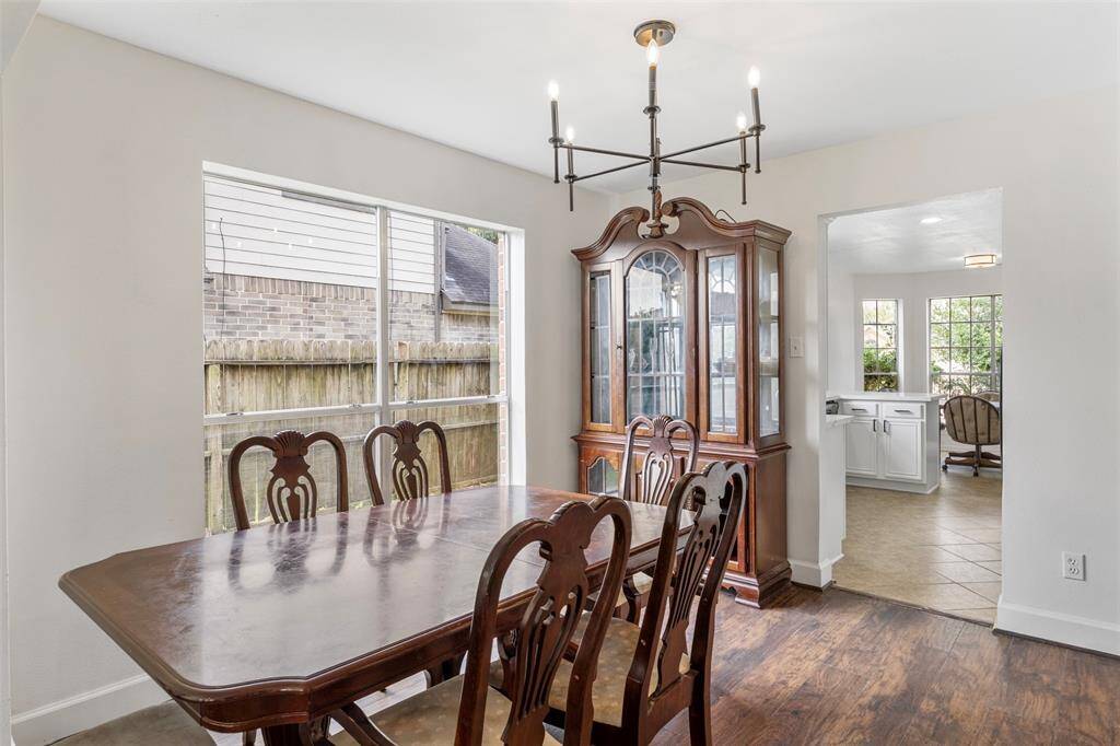 Another view of dining room features a large window providing natural light. The space is connected to a bright kitchen, enhancing the home's open feel.