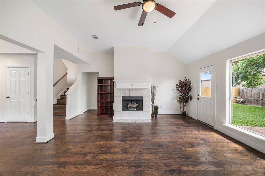 Cozy family room featuring a charming fireplace, high ceilings with convenient stairs leading to the upper level.