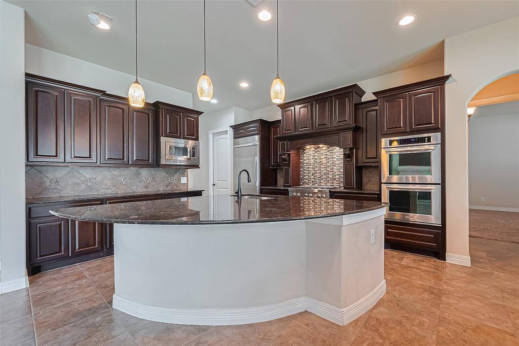 The oversized island in the kitchen has room for about 6 people. Kitchen has 3 mosaic matching pendant lights as well as a 36" commercial grade Kitchen Aid refrigerator and Kitchen Aid dishwasher and upper and lower ovens. Cabinets are benedettini.