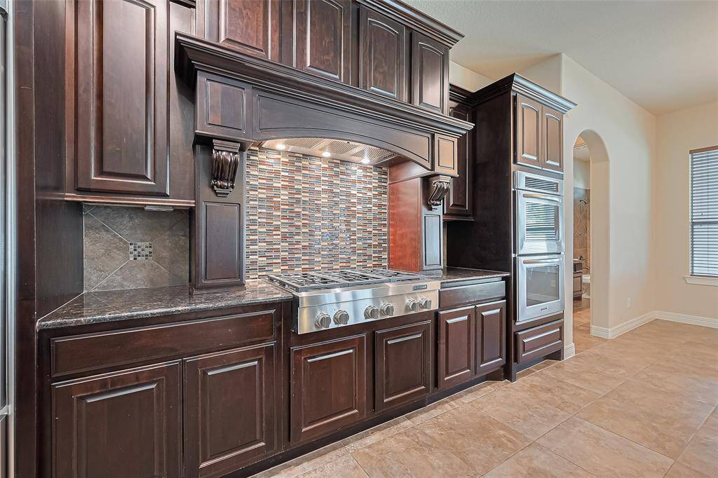 At an impressive 15x14 measurement, the kitchen also includes 36" Jenn Air commercial 6 burner cook top, custom made hearth with dual pull out storage racks and tile backsplash with square glass inlay.