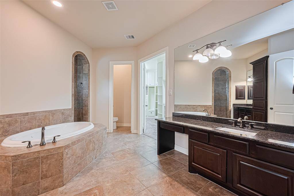 Primary bathroom has dual vanities with granite countertops, vanity lights and make-up vanity.