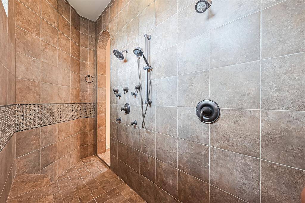 13 foot double arched walk-in shower that has 3 shower heads, body sprayer, built-in bench and basket weave ribbon with rope border.