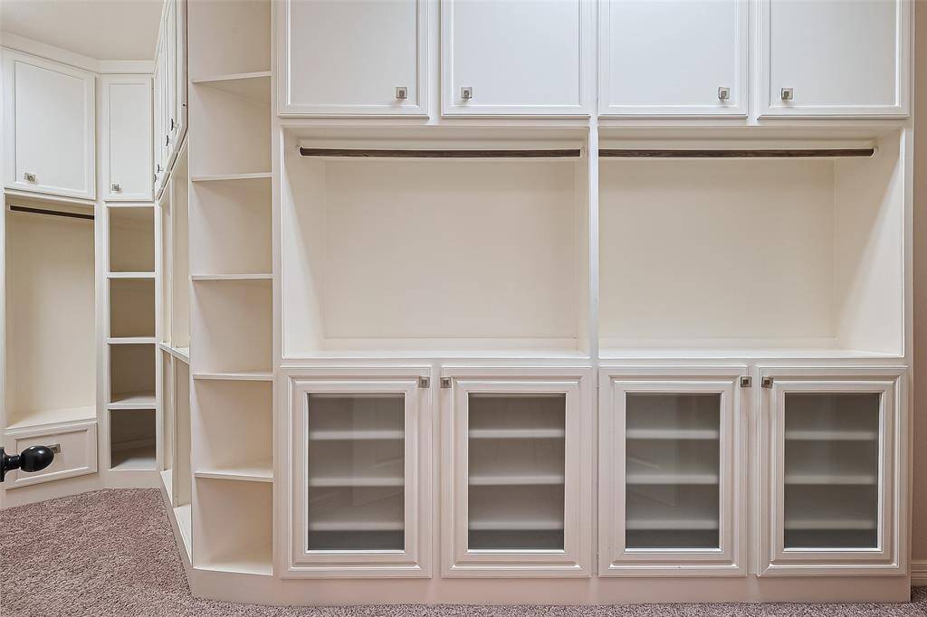 The custom detailed closet has built-ins, glass insert panels and glass pull knobs.