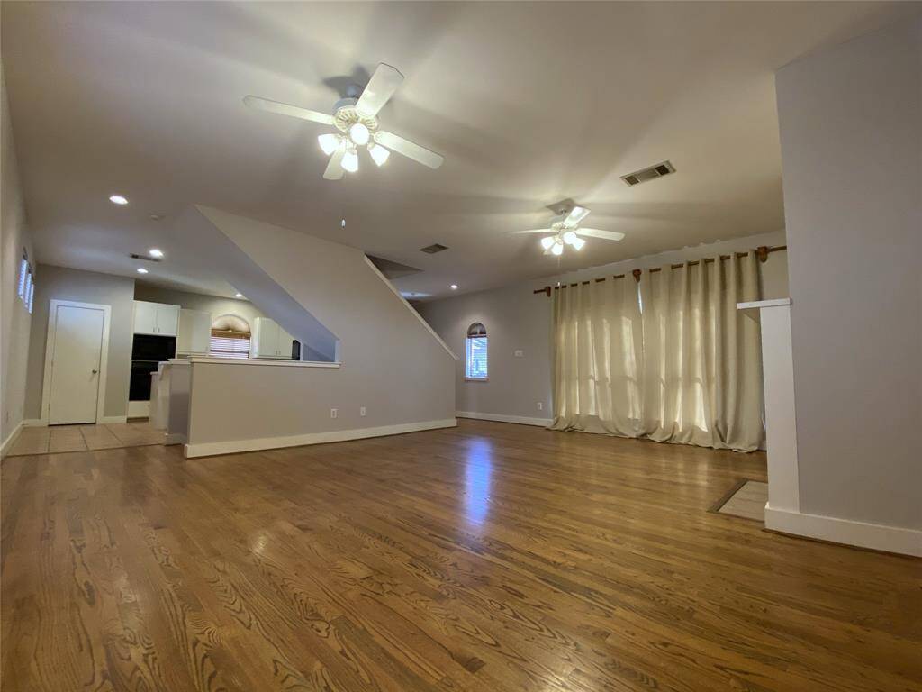 Alternate view of the living/dining room with two ceiling fans/light fixtures & window coverings.