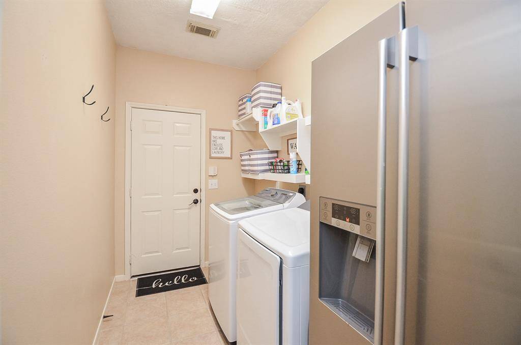 Large indoor utility room with shelving and plenty of room for a second refrigerator, freezer or create a mud room space.