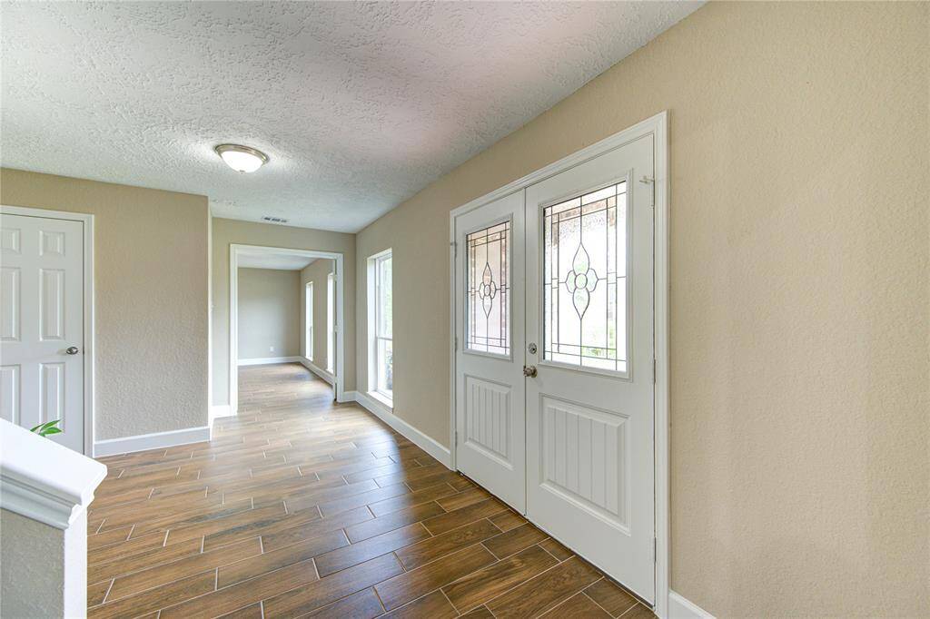 Another view of the bright entryway with elegant double doors featuring decorative glass, leading to a hallway and office. New windows throughout the house.