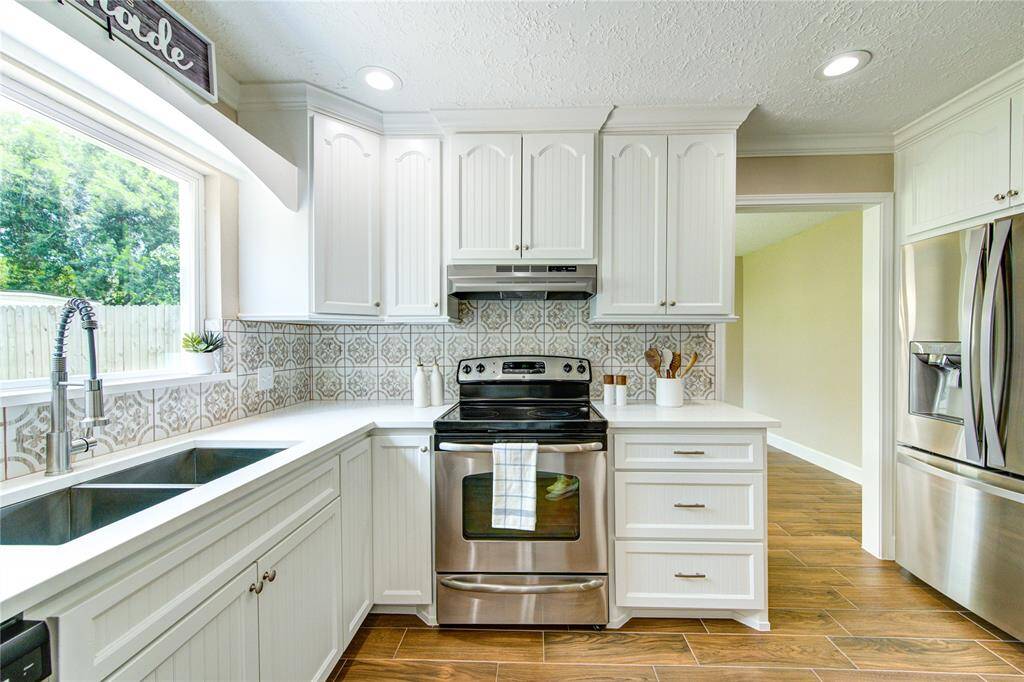 Another view of the bright and open kitchen with ample lighting and idyllic picture window facing the backyard.