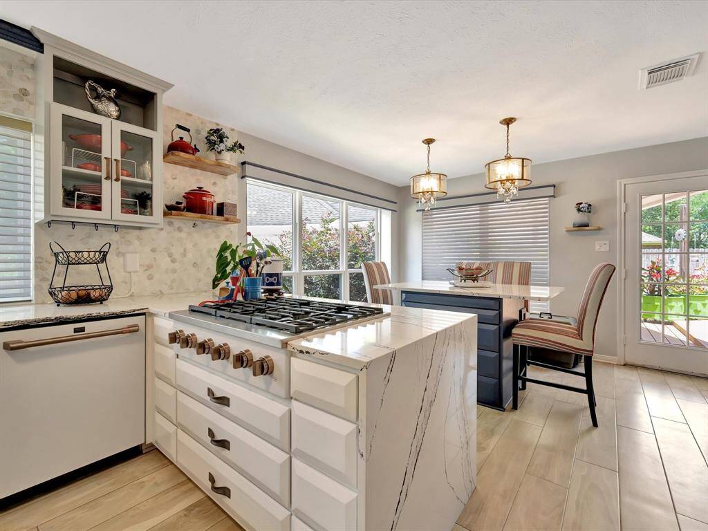 The kitchen features a premium GE Café 6-burner rangetop, perfect for culinary enthusiasts seeking both power and precision. Complementing the setup is a sleek GE dishwasher (2022), offering quiet, efficient performance. Both are seamlessly integrated into the quartz countertop design for a sophisticated, functional cooking space
