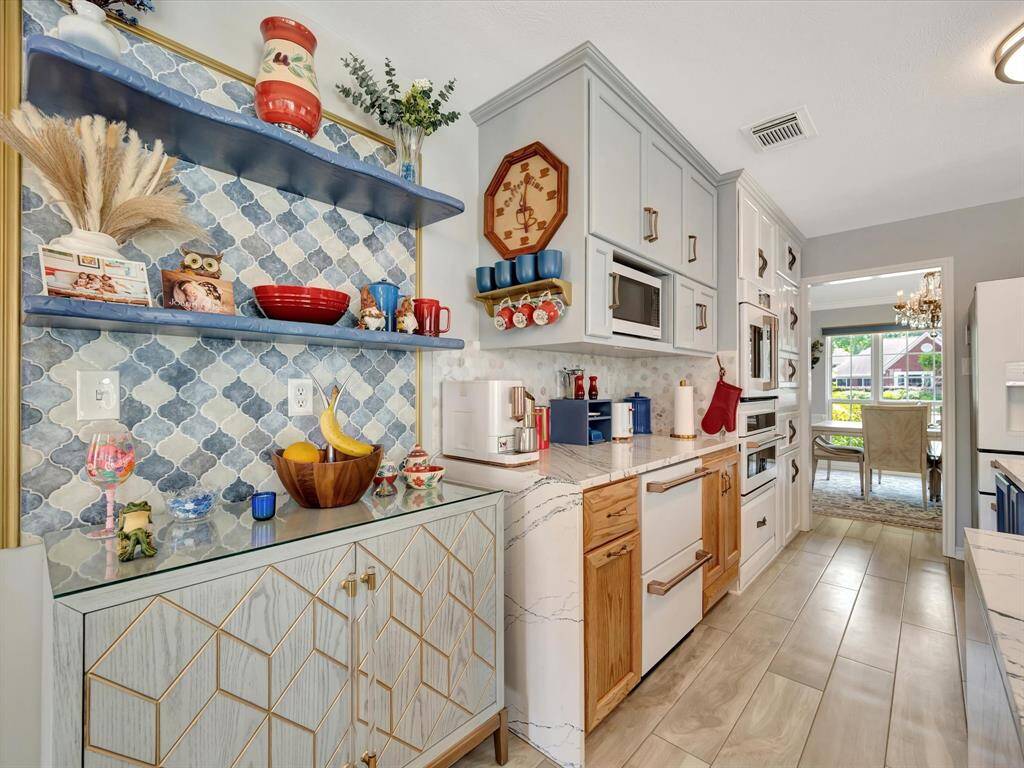 All kitchen cabinets and drawers feature sleek push-to-open mechanisms, maintaining clean lines while concealing advanced smart organization systems. The space includes a GE Café undermount refrigerator, an electric oven/microwave combo, and a French door convection oven—all seamlessly integrated with elegant quartz countertops for a modern and highly functional kitchen.