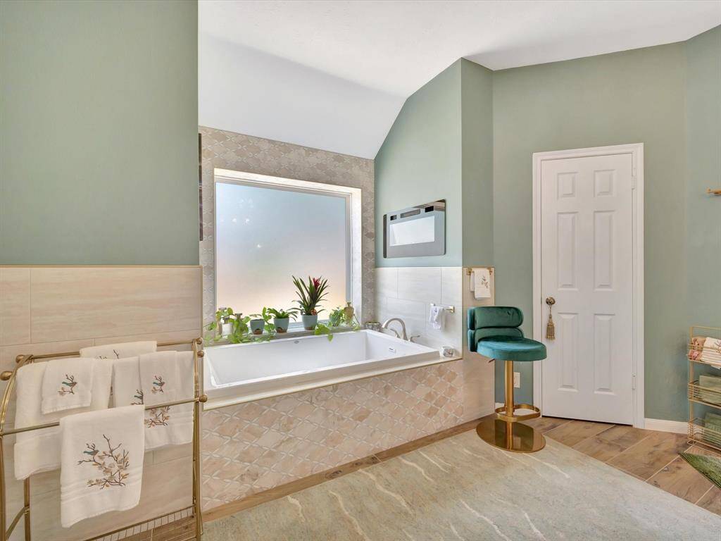 The elegant James Martin vanity is topped with a custom countertop, offering a perfect blend of style and functionality. It is flanked by custom cabinets that cleverly conceal electrical outlets, a hamper, and additional storage—providing a clean, organized, and luxurious space.