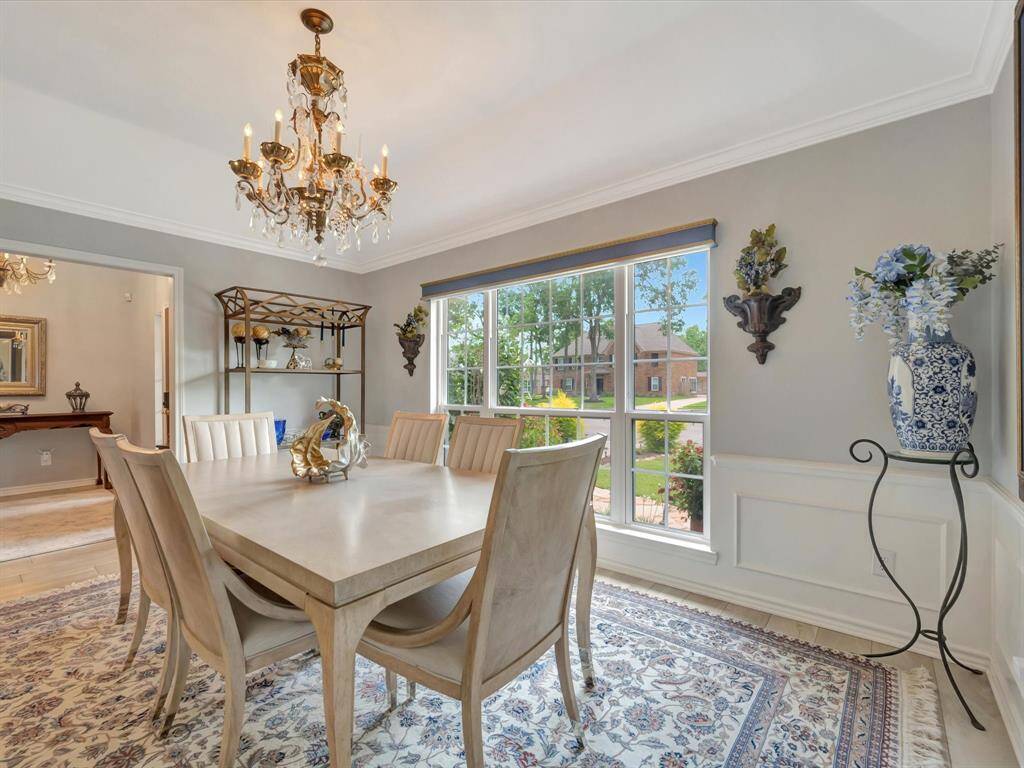 The dining room exudes timeless charm with wood paneling along the lower walls, adding warmth and character to the space. Large vinyl windows bring in natural light, while an elegant chandelier serves as a stunning focal point, perfect for both everyday dining and special occasions.