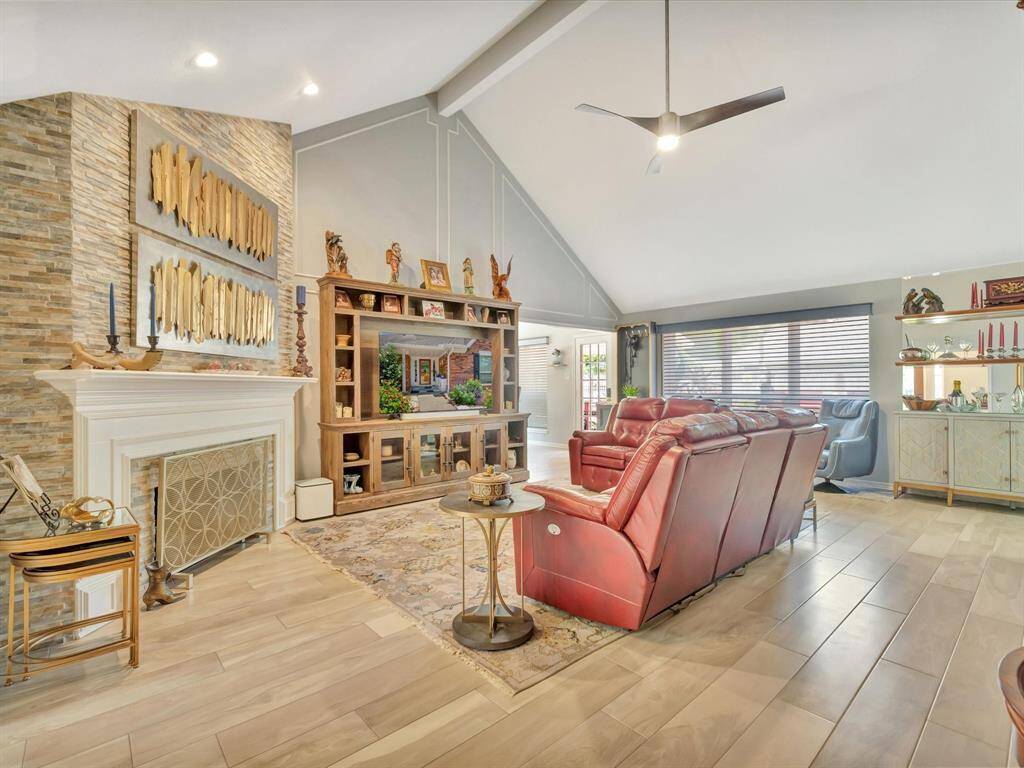 A striking floor-to-ceiling stone surround highlights the fireplace, which features a classic wood mantle—offering both warmth and a beautiful focal point for the space.