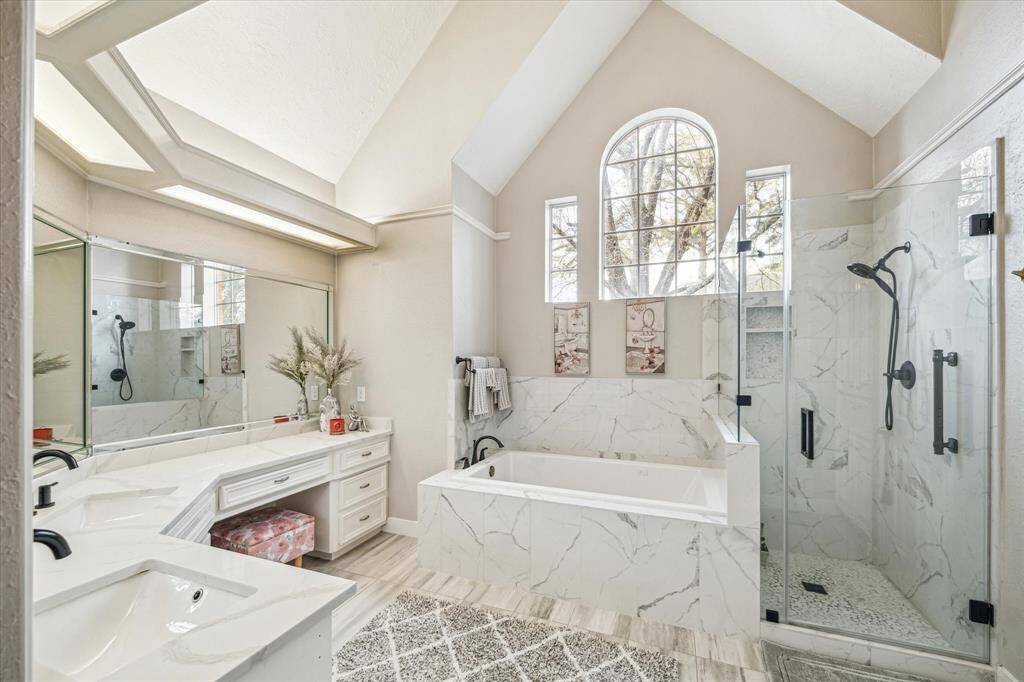 Stunning cathedral-style master bathroom featuring double sinks, a separate shower, and a soaking tub. Recently updated with modern finishes.