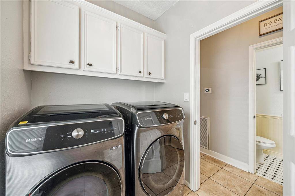 Utility room located on the first floor, featuring convenient overhead storage cabinets.