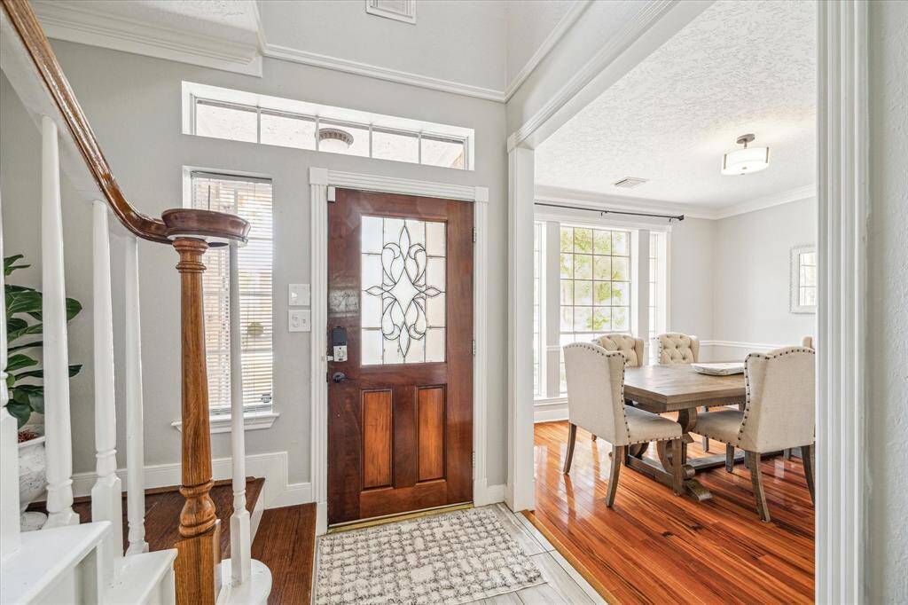 View of the front door and the beautifully updated staircase featuring rich wooden steps.