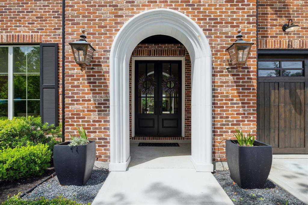 Beautiful entry way with a concrete arch and double doors. Custom landscaping from front to back exterior.