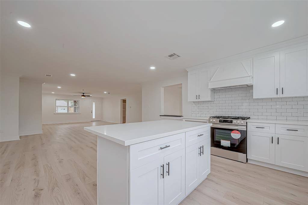 Seamless sightlines from the quartz-topped island to the expansive living area keep the chef connected, while new stainless appliances, subway tile, and abundant shaker cabinetry make meal prep a breeze.