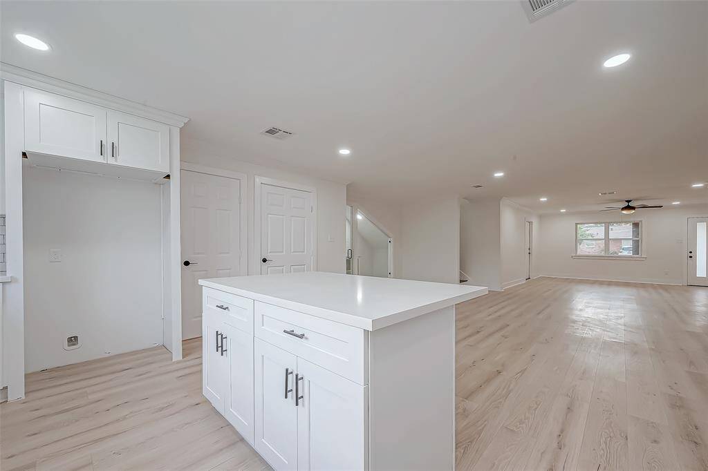Central quartz-topped island delivers extra storage and casual seating, all while maintaining effortless flow to the living area—flanked by a pantry, future fridge niche, and easy access to the staircase and side entry for everyday convenience.