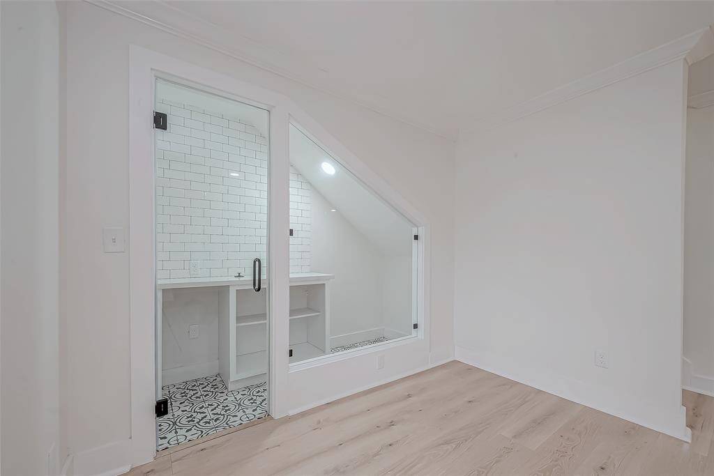 Chic glass-enclosed flex nook features eye-catching patterned tile, subway-tile walls, and built-in shelving—ideal for a coffee bar, mini office, or playful kids’ hideaway.