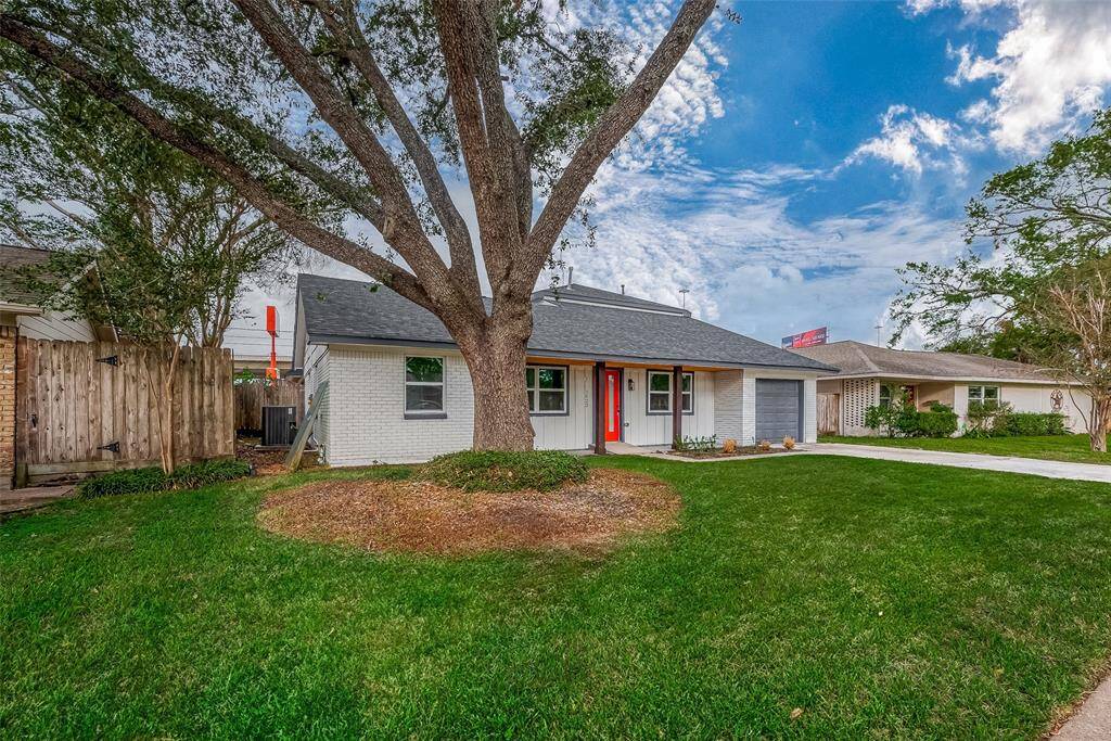 Striking curb appeal abounds with crisp white brick, board-and-batten accents, and a bold red front door, all nestled beneath a sprawling live oak that adds character and cooling shade for those balmy Texas afternoons.