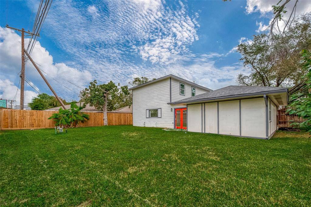 Updated rear façade pairs crisp white siding and gray trim with vibrant red French doors leading from the two-story addition into a sprawling, lush backyard—an ideal backdrop for weekend barbecues or evening stargazing.